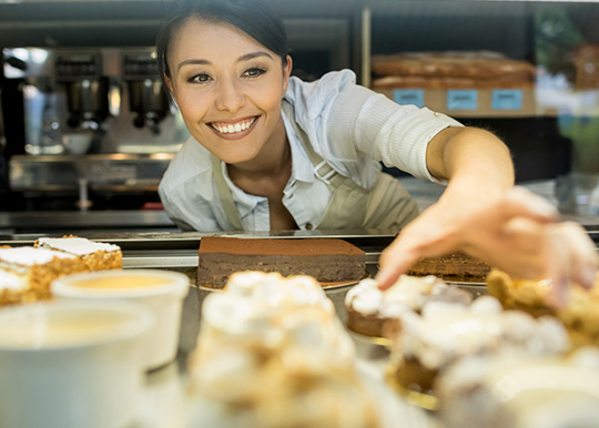 Woman reaching into refrigerated case for pastries